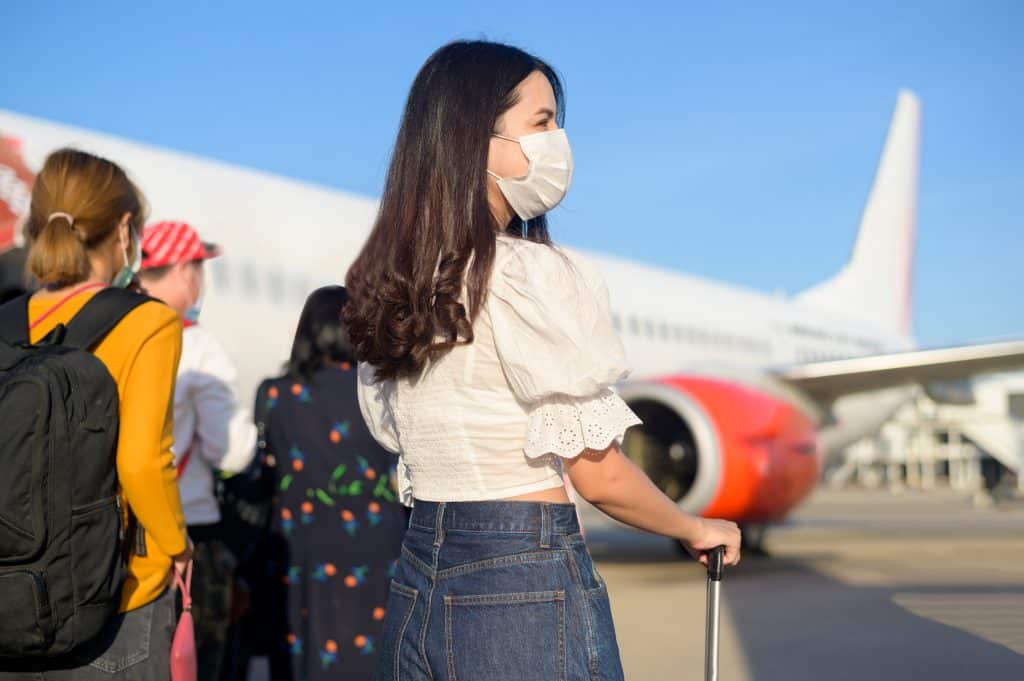 A Young Woman Traveler Wearing,Protective Mask Getting In Airplane